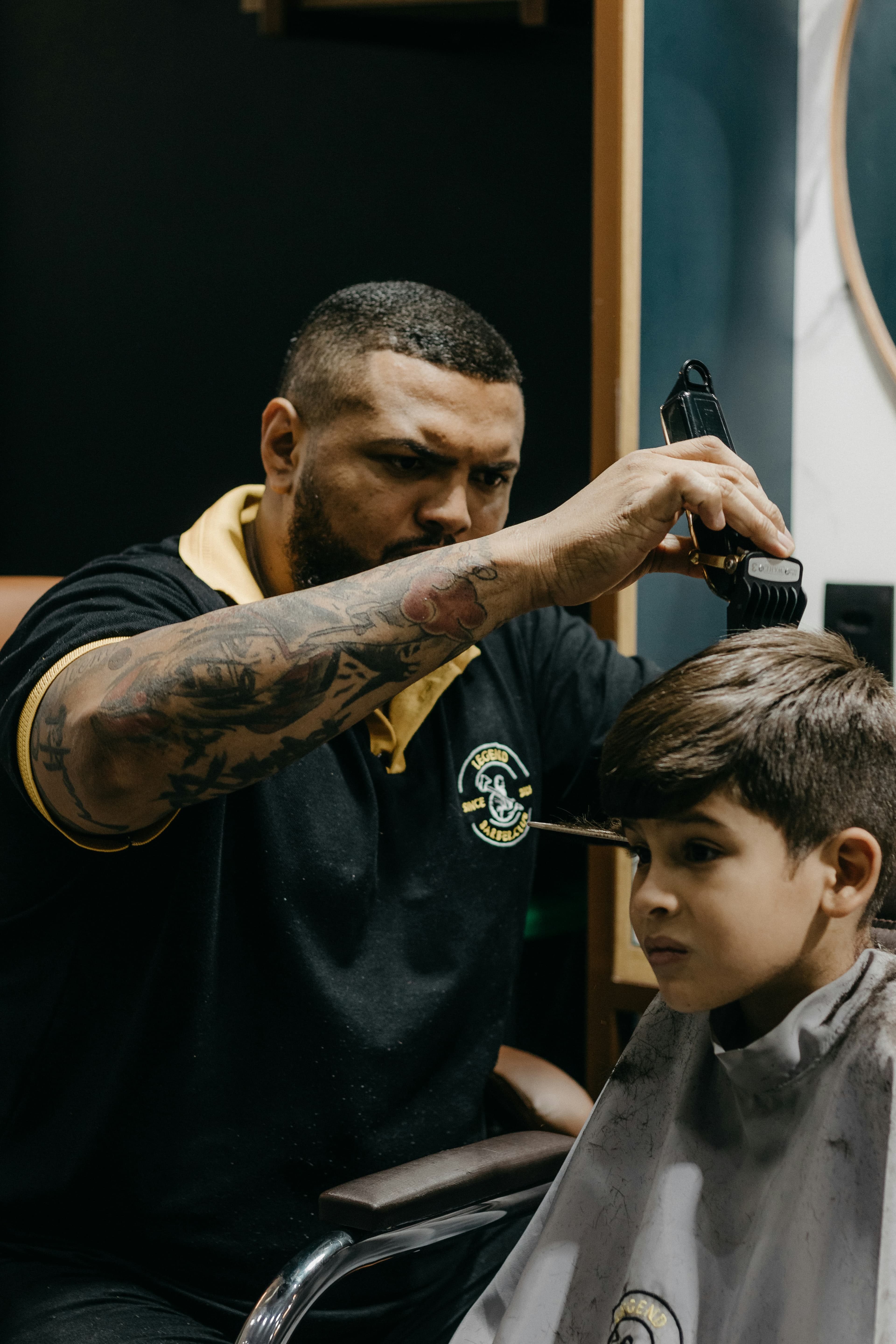 Barber trimming a young boy’s hair with clippers and a comb