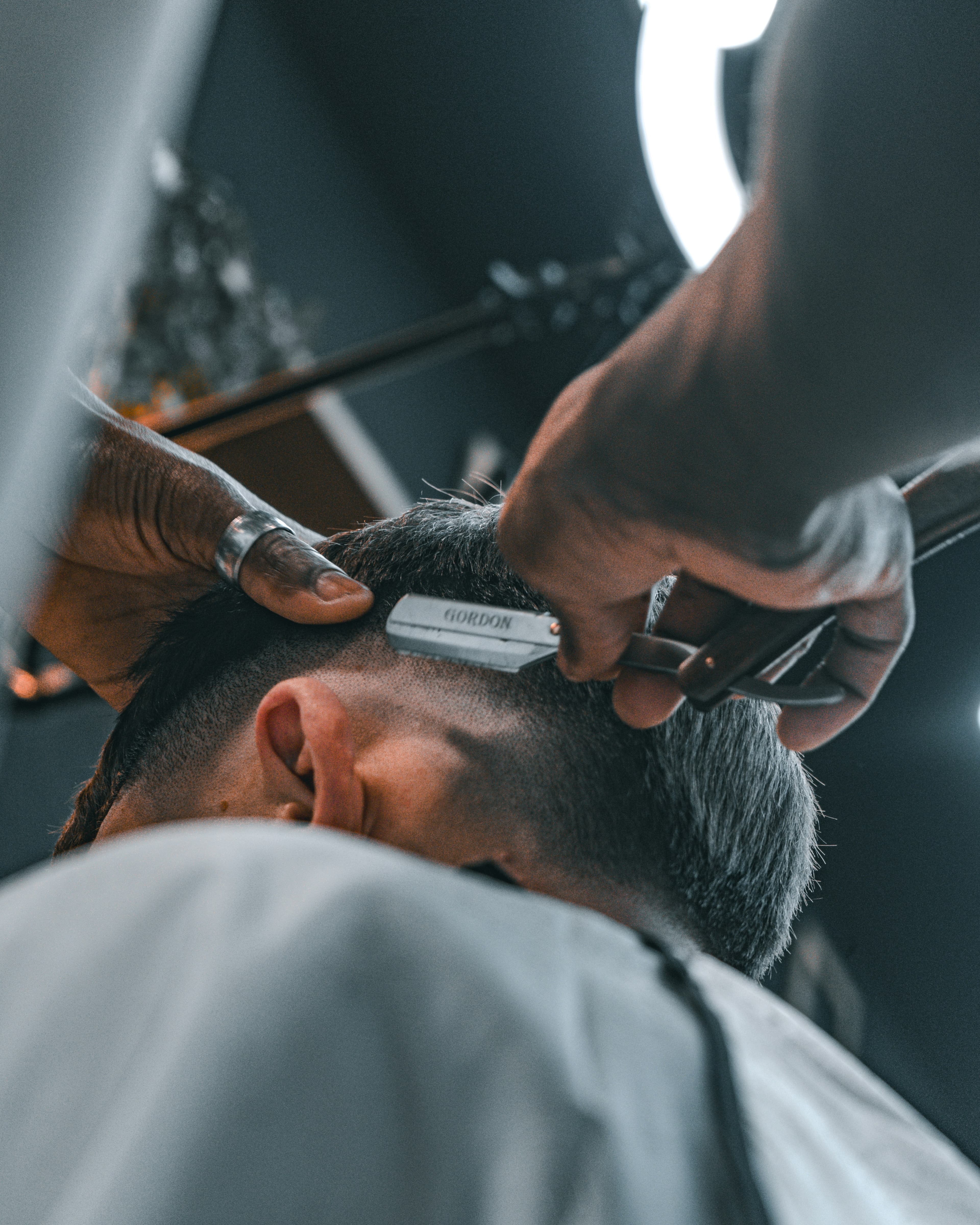 Barber cleaning up a client’s neckline with a straight razor