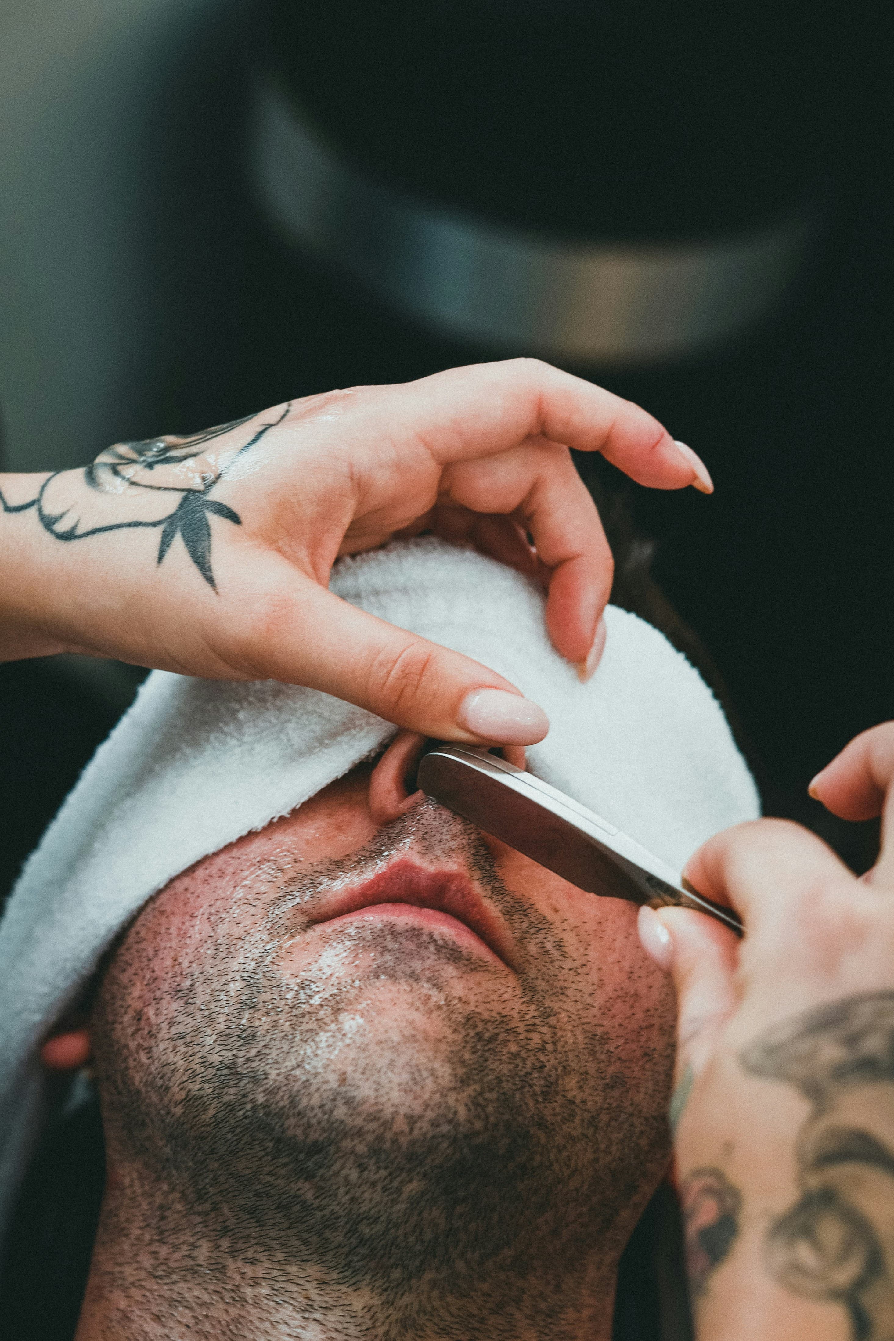 Client under a warm towel receiving a straight razor shave